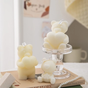 Close-up of cream-colored bear candles with heart details on books and pearl necklace