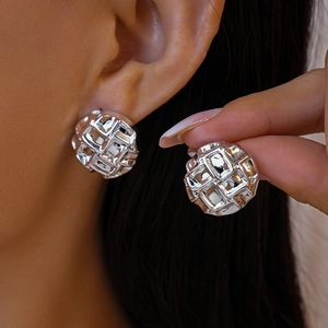 Détail de boucles d'oreilles en acrylique argenté à texture irrégulière sur modèle et main