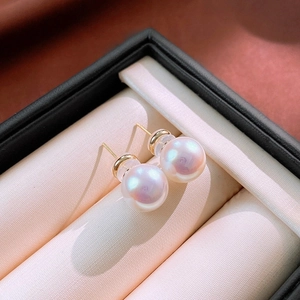 Macro shot of lustrous pink pearl earrings with gold pins in a premium jewelry box