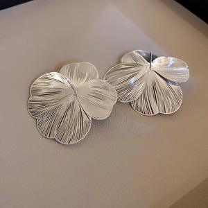 Macro shot of silver flower earrings with detailed brushed metallic texture and studs