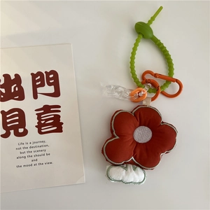 Detail of embroidered floral fabric charm with orange petals and green wavy silicone strap
