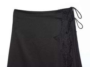 Close-up of black satin wrap skirt featuring intricate lace trim and tie waist detail