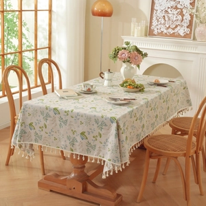 Close-up of beige linen tablecloth with floral patterns and delicate fringe trim