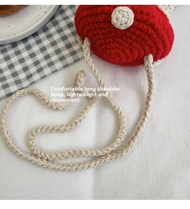 Detailed close-up of a red handmade crochet crossbody bag with thick cream rope strap