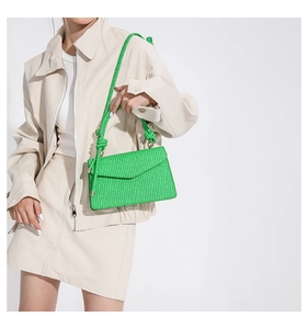 Detail of green woven crossbody bag texture with matching rope strap on a model