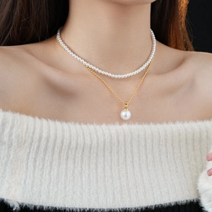 Detail view of double-layer gold plated necklace with artificial pearls on a model