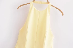 Detail of light yellow halter neck dress with vertical seam and structured bodice fit