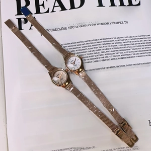 Close-up of rose gold quartz watches with mesh metal straps on a magazine background