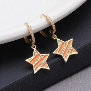 Macro shot of gold star drop earrings with micro-inlaid zircon and orange enamel details