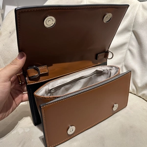 Brown leather crossbody bag with dual magnetic closures and spacious wave-lined interior