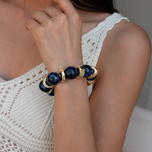 Detail of bohemian bracelet with blue marble beads and golden textured metal charms