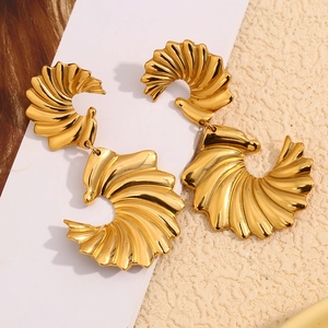 Vue macro de boucles d'oreilles ailes dorées à l'or 18 carats avec texture polie