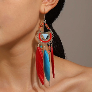 Close-up of model wearing bohemian long feather earrings with red and blue beads