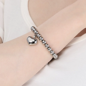 Close-up of minimalist 18K gold-plated beaded bracelet with a large heart pendant on wrist