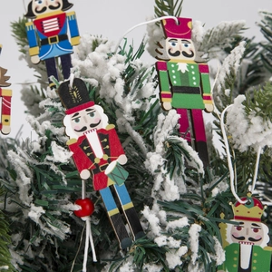 Classic wooden nutcracker ornaments hanging on snowy green Christmas tree branches