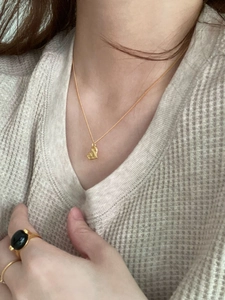 Detailed view of a textured gold heart pendant necklace styled with vintage gold rings