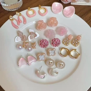 Pink floral and pearl stud earring set with gold accents on a white ceramic plate
