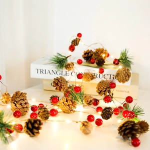 Close-up of LED warm white fairy lights with pine cones and red berries for Christmas decor