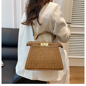Detail of brown woven leather handbag with gold twist lock on a white suit model