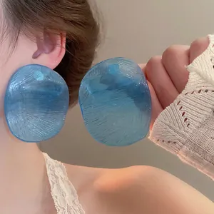 Blue oversized translucent acrylic earrings with brushed texture on model