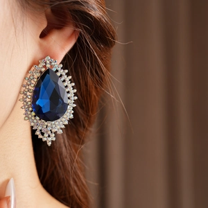 Close-up of a blue teardrop earring with rainbow crystals on a female model