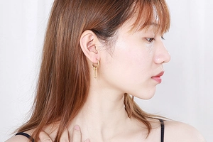 Detailed view of layered gold circular tube drop earrings on model in minimalist style