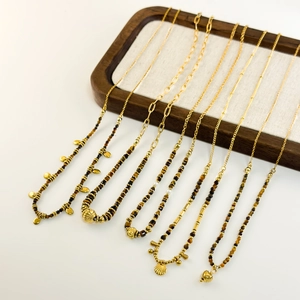 Faceted tiger eye beaded necklaces with golden charms on wooden display stand