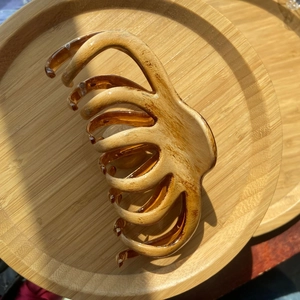 Macro detail of amber tortoiseshell hair claw clip on a rustic wooden display tray