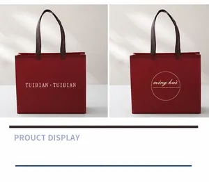 Detailed view of red non-woven gift bag featuring elegant branding and coffee brown handles