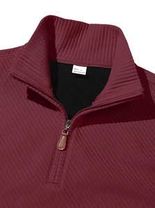 Detail shot of men's burgundy quarter-zip sweatshirt with rib-knit texture and collar label