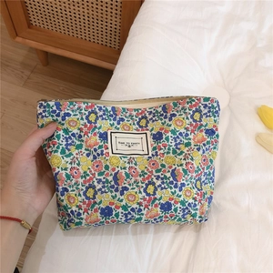 Detail of floral cotton makeup bag with zipper and Time to Party label held by a hand