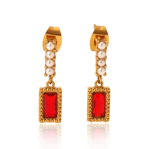 Macro shot of vertical white pearls and red rectangular gemstone earrings in gold finish