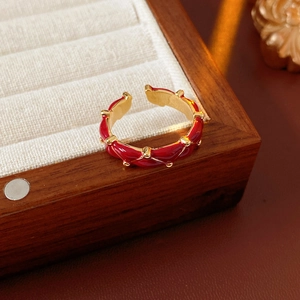 Macro detail of gold-plated twisted ring with red enamel finish on a velvet display