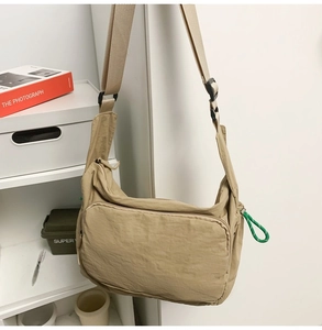 Detail of khaki nylon messenger bag with zipper pocket and green rope knot tassel