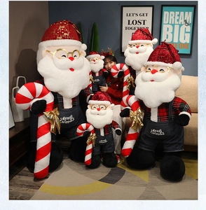 Detail of oversized Santa plush dolls with Merry Christmas embroidery and red plaid outfits