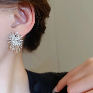 Close-up of a sparkling silver snowflake stud earring worn on the earlobe with zircons
