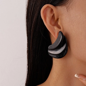 Detail of oversized black resin earrings with a triple-layered geometric crescent design