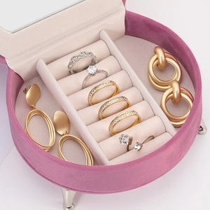 Pink velvet circular jewelry organizer with internal ring slots and lid mirror