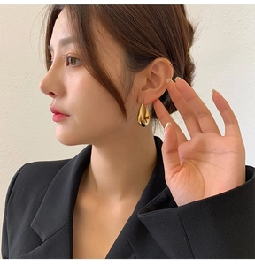 Close-up of elegant gold teardrop earrings with high-polish finish on a model