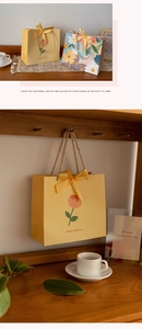 Detail of warm yellow floral gift bag featuring a silk bow and woven handle on wood