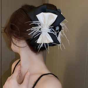 Detail view of bow hair claw clip with black ribbons, white feathers and pearls decor