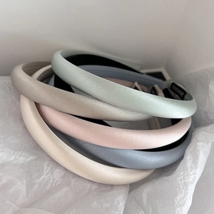 Five silk satin headbands in pastel colors stacked neatly for a minimalist hair accessory look
