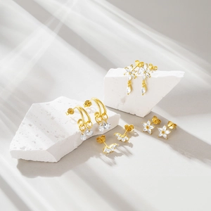 Detail of gold floral and butterfly earrings with cubic zirconia on stone base