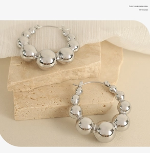 Detailed shot of silver gradient beaded hoop earrings on minimalist stone texture background