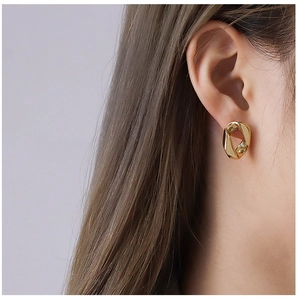 Gros plan de boucles d'oreilles géométriques irrégulières en acier doré 18 carats sur modèle