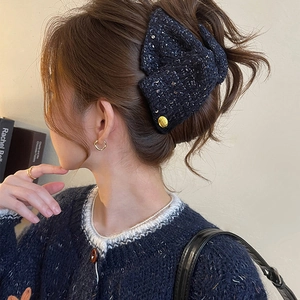 Elegant navy blue sequin fabric bow hair claw clip with golden accent on female model