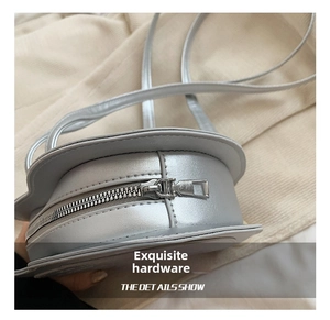 Close-up of durable metal zipper and metallic finish on a silver round shoulder bag