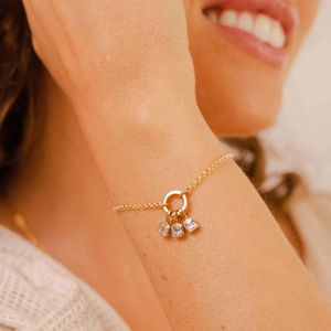 Detail view of gold chain bracelet with three square lavender birthstone pendants