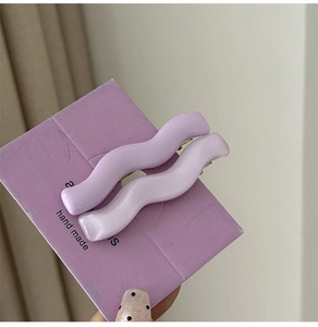 Close-up of handmade lavender wavy hair clips set on a display card with wave design