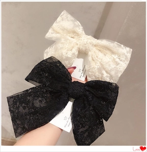 Detailed view of cream and black lace bow hair clips with delicate embroidery patterns